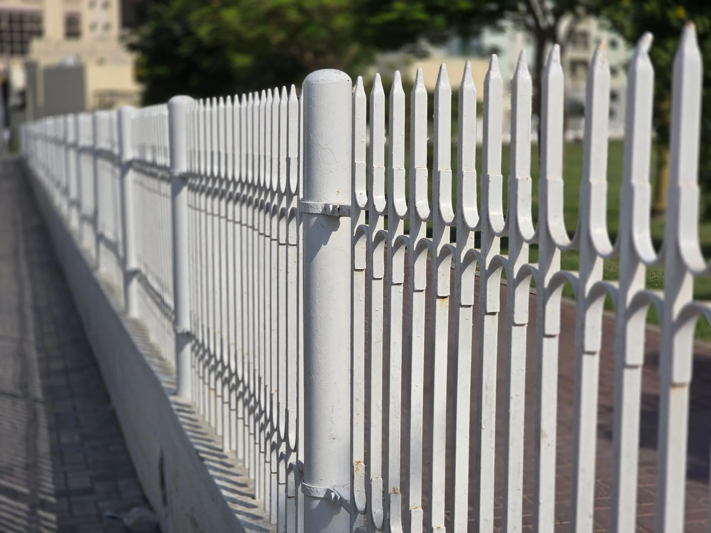 White steel palisade perimeter fencing with buildings behind